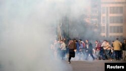 FILE - Anti-government protesters and members of the Muslim Brotherhood flee after teargas was fired by riot police during clashes in downtown Cairo, on the third anniversary of Egypt's uprising, Jan. 25, 2014. 