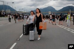 Pasajeros caminan hacia el aeropuerto después que manifestantes prodemocracia bloquearon una carretera afuera del aeropuerto de Hong Kong, el domingo 1 de septiembre de 2019. El servicio de trenes al aeropuerto se suspendió el domingo cuando los manifestantes se reunieron allí. AP/Kin Cheung.