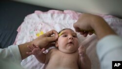 In this Dec. 22, 2015 photo, a baby named Luiza has her head measured by a neurologist in Caruaru, Brazil. Luiza, a Zika victim, was born in October with a head that was just 11.4 inches (29 centimeters) in diameter, below the range defined as healthy by