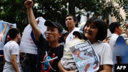 FILE - Tran Thi Nga, right, holds her son and an anti-China poster as she takes part in a rally in Hanoi, July 8, 2012.