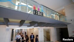 FILE - Employees pass under a logo at Deezer's headquarters in Paris, France, Sept. 5, 2017. 