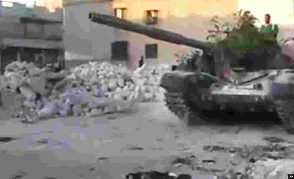 This image from amateur video released by the Ugarit News shows a Free Syrian Army solider driving a Syrian military tank in Aleppo, Syria, July 24, 2012.