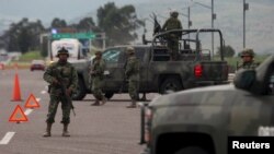 Soldiers stand guard at a checkpoint near Contepec, in Michoacan state, after Mexico's most notorious drug lord, Joaquin "El Chapo" Guzman, broke out of a high-security prison Saturday for the second time, escaping in a tunnel built right under his cell,