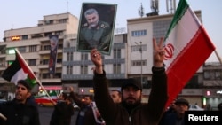 Un hombre sostiene una foto del difunto general Qassam Soleimani, el 8 de enero de 2020, mientras la gente celebra en las calles de Teherán, Irán, el lanzamiento de misiles a bases iraquíes que albergan soldados estadounidenses.