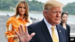 FILE - U.S. President Donald Trump, right, and First Lady Melania Trump arrive at the Japanese destroyer JS Kaga, in Yokosuka, south of Tokyo.