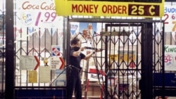 FILE - In this April 30, 1992 file photo, an L.A. police officer takes aim at someone attempting to steal something from a market in L.A. during the second night of rioting in the city in response to the acquittal of four police officers in the videotaped beating of Rodney King. (AP Photo/John Gaps III, File)
