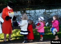 Britain's Queen Elizabeth receives flowers from children as she leaves a Christmas Day morning service at the church on the Sandringham Estate in Norfolk, eastern England, Dec. 25, 2013.