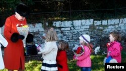 Britain's Queen Elizabeth receives flowers from children as she leaves a Christmas Day morning service at the church on the Sandringham Estate in Norfolk, eastern England, Dec. 25, 2013.