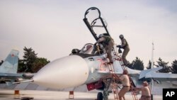 Un pilote russe monte dans son engin sur la base aérienne de Hemeimeem en Syrie, le 22 octobre 2015. (AP Photo/Vladimir Isachenkov, File)