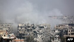 Smoke billows following Syrian government bombardment on the rebel-held besieged town of Harasta, in the Eastern Ghouta region on the outskirts of Damascus, March 12, 2018. 