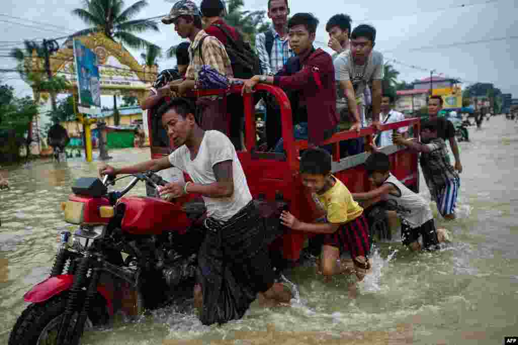 Warga mendorong kendaraan melalui jalanan yang tergenang banjir di wilayah Bago, sekitar 68 km dari Yangon, Myanmar.
