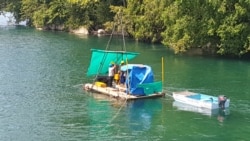 etugas dari PT. Poso Energy yang sedang melakukan kegiatan pengeboran dari atas sebuah perahu ponton tidak jauh dari situs cagar budaya Gua Pamona drilling indari atas kapal. Jumat (19/02/21). (Foto: VOA/Yoanes Litha)