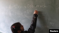 FILE - A Syrian refugee girl writes "we miss Syria too much" on the chalkboard in her classroom in Majdel Anjar in Bekaa Valley December 27, 2012.