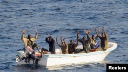 Des pirates présumés lèvent les mains en l'air suivant l’ordre des marins qui les interpellent depuis un lance-missiles USS Vella Gulf (CG 72) (non visible sur l’image), dans le golfe d'Aden, le 11 Ffévrier 2009.