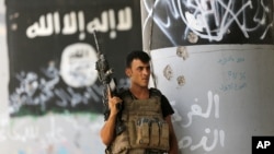 A member of Iraqi counterterrorism forces stands guard near Islamic State militant graffiti in Fallujah, Iraq, June 27, 2016.