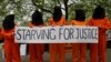 Protesters depicting detainees of the US detention facility at Guantanamo Bay, Cuba, hold a banner, during a demonstration outside the US embassy in central London, May 18, 2013.