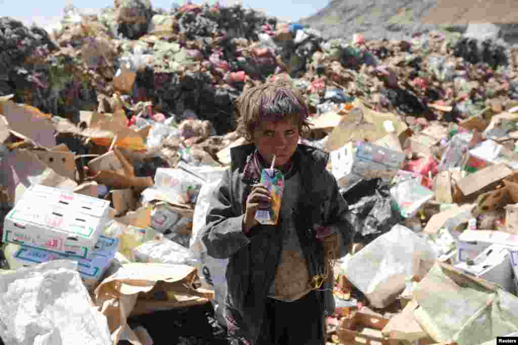 Yemen&#39;de bir çocuk çöplüğün ortasında son kullanma tarihi geçmiş bir meyve suyunu içiyor