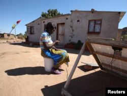 FILE - A women checks a message on her mobile phone in Epworth, east of the capital Harare, Zimbabwe, Aug. 11, 2016.