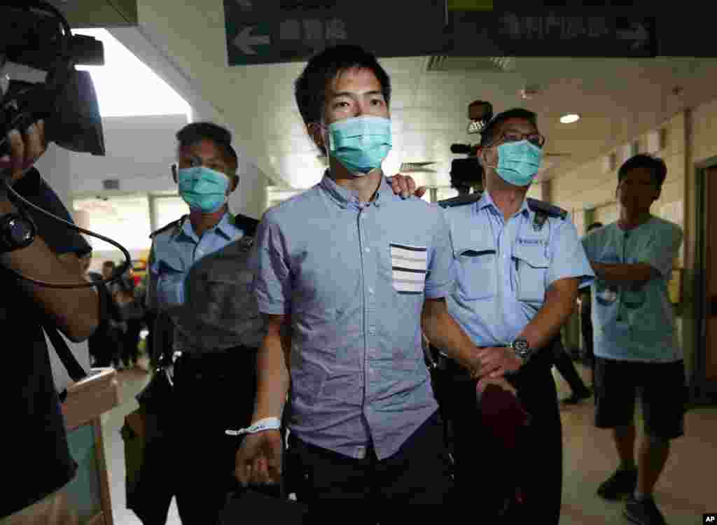 Seorang demonstran gerakan Occupy Central dikawal polisi ke rumah sakit karena luka dalam bentrokan antara demonstran dengan polisi dekat kantor-kantor pemerintahan di Hong Kong (15/10). (AP/Kin Cheung) 