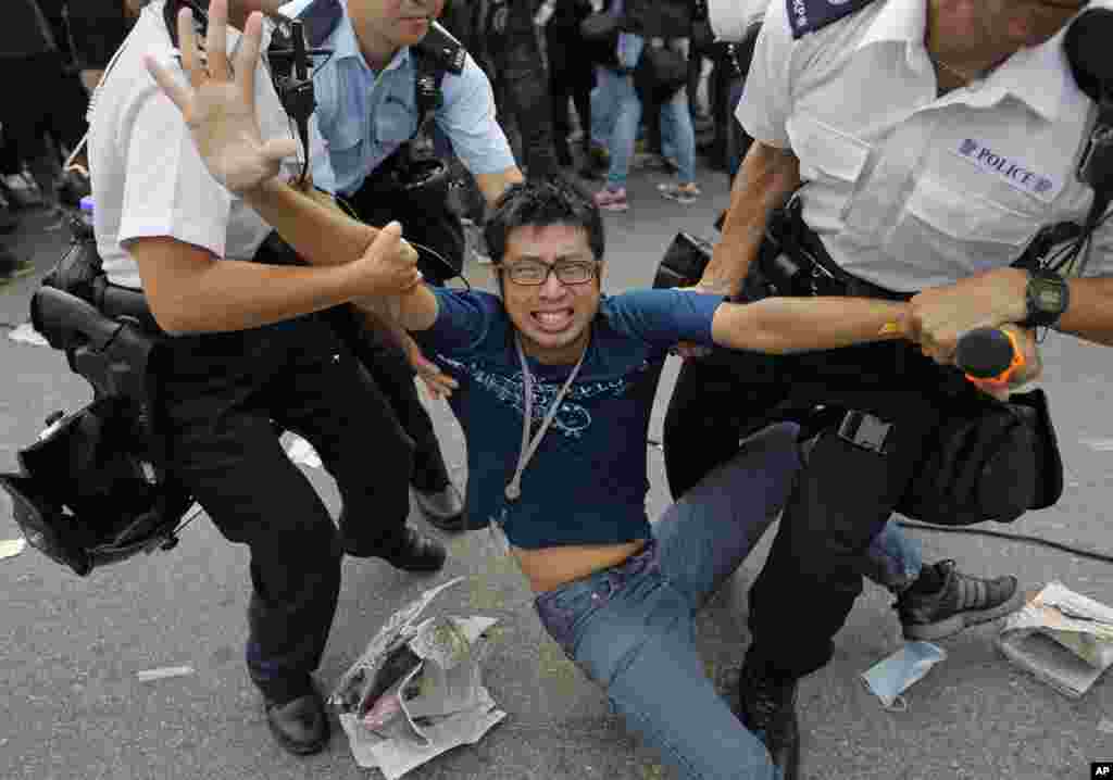 A pro-democracy protester is taken away by police offers as an ambulance tries to leave the compound of the chief executive office in Hong Kong.