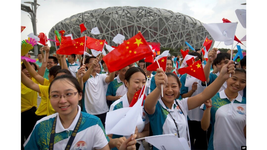 Participants wave flags and cheer before the announcement that Beijing will host the 2022 Winter Olympics at a gathering outside the Beijing Olympic Stadium, also known as the Birds Nest, in Beijing, July 31, 2015.