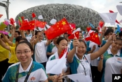 Participants wave flags and cheer before the announcement that Beijing will host the 2022 Winter Olympics at a gathering outside the Beijing Olympic Stadium, also known as the Birds Nest, in Beijing, July 31, 2015.