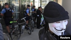 Un manifestante con una máscara de Guy Fawkes frente a miembros de la policía de Chicago, durante una de las protestas contra la reunión de la OTAN.