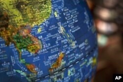 In this July 13, 2018, file photo, a globe shows the islands on the South China Sea with nine-dash line claims under Chinese territory on display at a bookstore in Beijing. draf