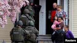 Polisi khusus melakukan pemeriksaan dari rumah ke rumah untuk mencari tersangka Dzhokar Tsarnaev di kota Watertown, Massachusetts, sementara warga diminta keluar rumah mereka (19/4). 