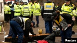  پلیس سعی دارد هواداران محیط زیست را که در برابر محوطه حفاری گازی خود را به تابوت زنجیر کرده اند، از محل خارج کند-منچستر انگلیس