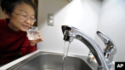 A woman fills a glass with water from a tap in Tokyo on March 23, 2011