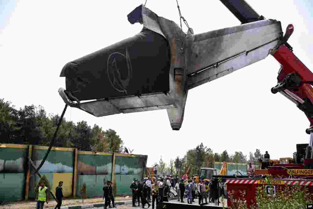 A firefighting crane lifts the tail section of a passenger plane which crashed near the capital Tehran, Iran, Aug. 10, 2014.