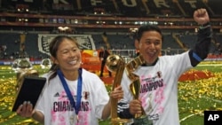 Japan's Homare Sawa (L) and head coach Norio Sasaki and pose with trophies after the end of their Women's World Cup final soccer match against the U.S. in Frankfurt, July 17, 2011