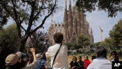 In this Thursday, May 26, 2016 file photo, tourists take pictures in front of Sagrada Familia church, designed by architect Antoni Gaudi in Barcelona, Spain. (AP Photo/Manu Fernandez, File)