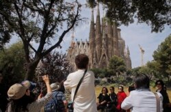 Turis berfoto di depan Gereja Sagrada Familia yang dirancang oleh arsitek Antoni Gaudi di Barcelona, Spanyol. (Foto: AP)