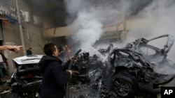 2014年 1月2日，黎巴嫩首都贝鲁特南部郊区发生汽车炸弹爆炸后，人们在现场救火，熄灭燃烧的车辆。