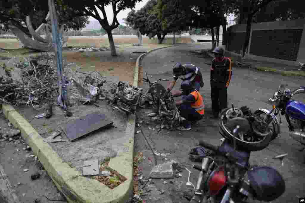 Men look to recover usable parts from motorcycles burned during the previous day's clashes between anti-government protesters and security forces in Caracas, Venezuela, Wednesday, May 1, 2019.