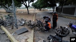 Men look to recover usable parts from motorcycles burned during the previous day's clashes between anti-government protesters and security forces in Caracas, Venezuela, Wednesday, May 1, 2019.