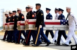 Military members carry transfer cases from a C-17 at a ceremony marking the arrival of the remains believed to be of American service members who fell in the Korean War at Joint Base Pearl Harbor-Hickam in Hawaii, Aug. 1, 2018.