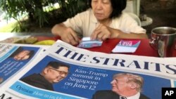 A news vendor counts her money near a stack of newspapers with a photo of U.S. President Donald Trump, right, and North Korea's leader Kim Jong Un on its front page on Friday, May 11, 2018, in Singapore.