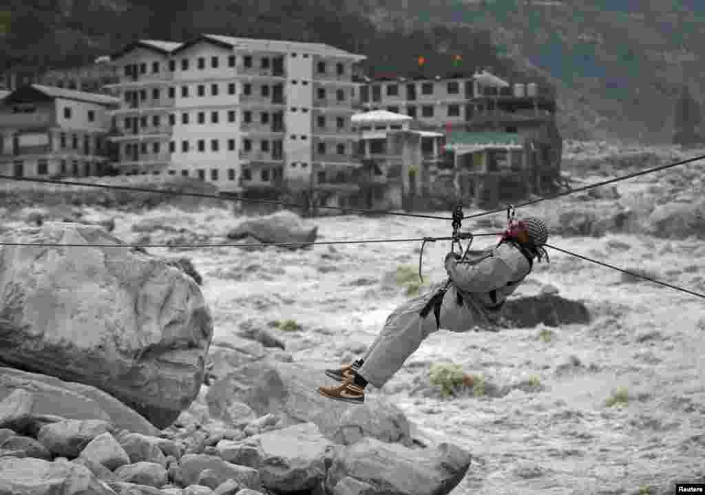 A man is pulled across to safety on a rope during a rescue operation in Govindghat in the Himalayan state of Uttarakhand as damaged buildings and the Alaknanda river are seen in the background. Flash floods and landslides unleashed by early monsoon rains have killed at least 560 people in Uttarakhand and left tens of thousands missing, officials said.