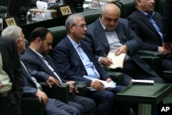 Iran's Labor Minister Ali Rabiei, center left, listens to a speaker during his impeachment hearing in an open session of parliament, in Tehran, Aug. 8, 2018.