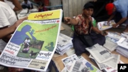 A man at a market in Rangoon, shows a People's Age private journal featuring an article written by Burma's pro-democracy leader Aung San Suu Kyi, September 6, 2011.