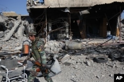 FILE- A Kurdish fighter walks past a destroyed building in the town of Sinjar, Iraq, after they took it from the Islamic State group in a joint operation with the coalition forces, Nov. 13, 2015.