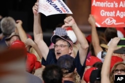 Supporters of President Donald Trump gesture to the media during a campaign rally, Feb. 18, 2017, in Melbourne, Florida. Some Trump rallies were organized by Russians, according to an indictment issued Friday.