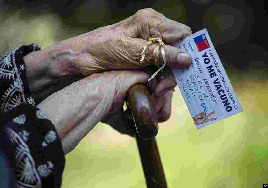 Alicia Martinez holds her vaccination card while resting after her second shot of China&#39;s Sinovac COVID-19 vaccine in the outdoor patio of a home for the elderly in Santiago, Chile.