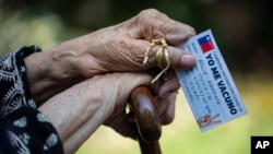 Alicia Martinez holds her vaccination card while resting after her second shot of China's Sinovac COVID-19 vaccine in the outdoor patio of a home for the elderly in Santiago, Chile.