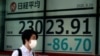 A man walks past an electronic stock board showing Japan's Nikkei 225 index at a securities firm in Tokyo, Aug. 20, 2020.