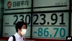 A man walks past an electronic stock board showing Japan's Nikkei 225 index at a securities firm in Tokyo, Aug. 20, 2020.