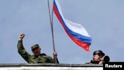 Pripadnik pro-ruskih snaga drži rusku zastavu u bazi ukrajinske mornarice u Sevastopolju